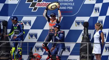 Pembalap Repsol Honda, Marc Marquez (tengah) mengangkat trofi usai keluar sebagai juara MotoGP Australia di Phillip Island (22/10). Dalam MotoGP Australia ini tempat kedua diisi Rossi dan ketiga menjadi milik Vinales. (AFP Photo/Paul Crock)