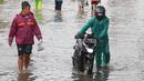 Warga berusaha melintasi genangan air ketika banjir merendam Jalan KH. Hasyim Ashari, Tangerang, Banten, Sabtu (16/7/2022). Akibat luapan kali angke ruas jalan yang menghubungkan Tangerang-Jakarta itu terputus akibat banjir. (Liputan6.com/Angga Yuniar)