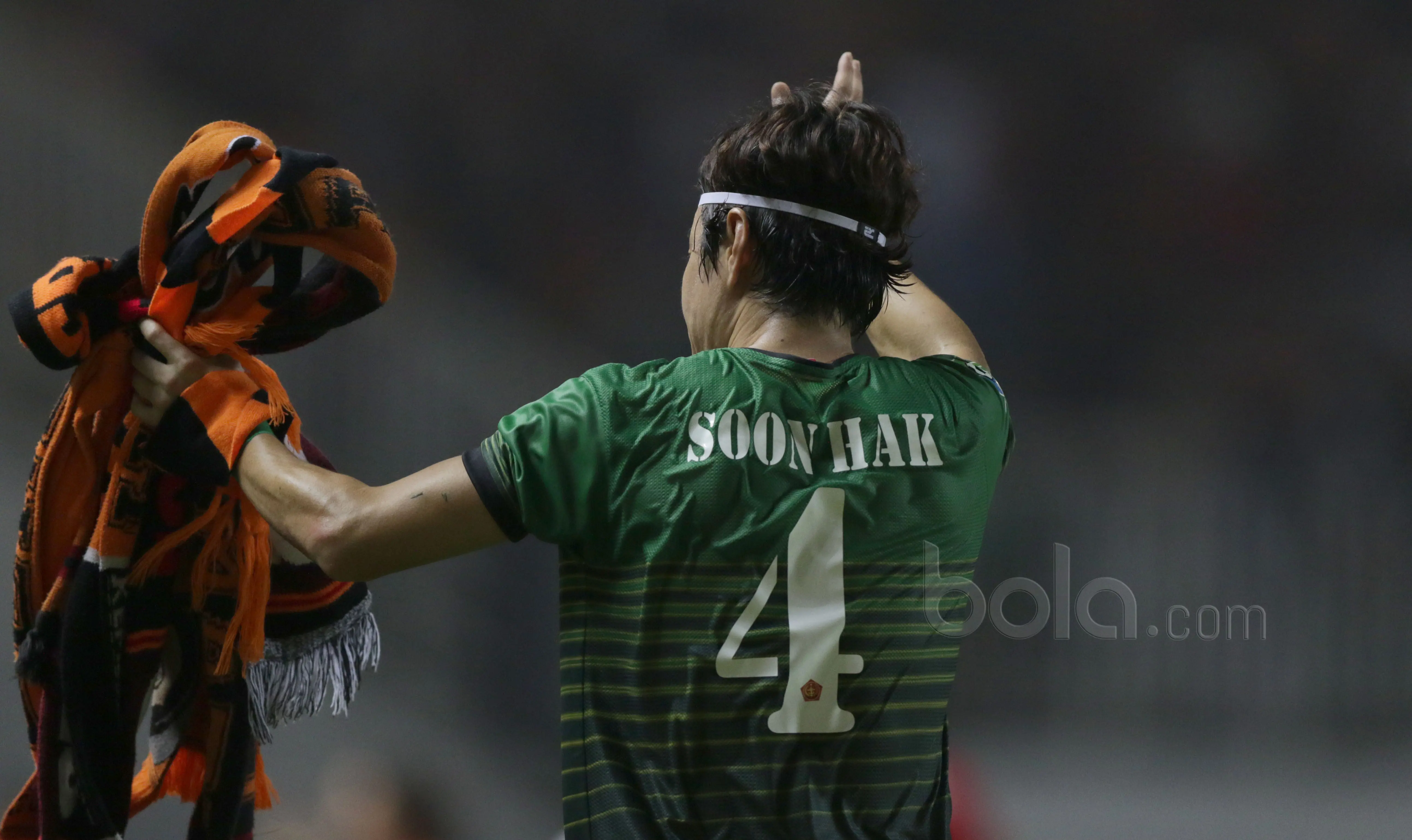 Sosok belakang Hong Soon-hak ketika memutar tribun dan memberikan penghormatan kepada The Jakmania. Sejumlah atribut Persija yang dilemparkan The Jakmania pun diambilnya. (Bola.com/Nicklas Hanoatubun)