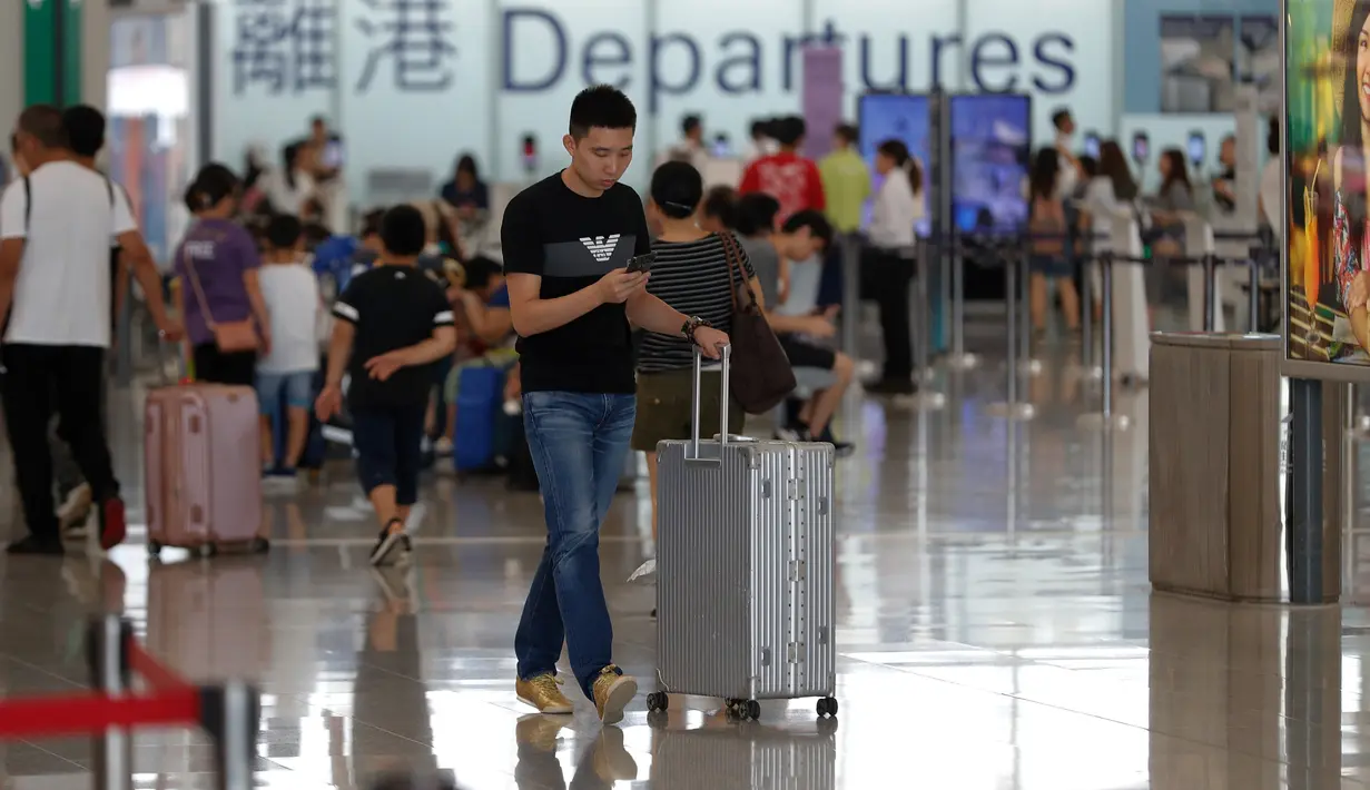 Calon penumpang mendorong koper ketika menunggu jadwal penerbangan di aula keberangkatan bandara di Hong Kong, Rabu (14/8/2019). Bandara Hong Kong kembali membuka penerbangan keberangkatan pada Rabu pagi setelah sempat lumpuh selama dua hari terakhir akibat demonstrasi. (AP/Vincent Thian)