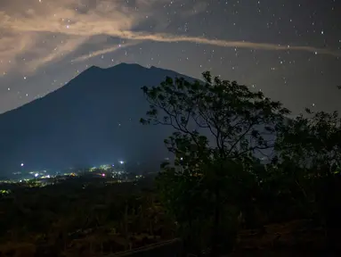 Pemandangan malam Gunung Agung di bawah langit penuh bintang terlihat dari Kubu di Karangasem, Bali, (28/9). Gunung Agung sejak sepekan lalu masih bertahan dengan status awas atau Level IV. (AFP Photo/Bay Ismoyo)