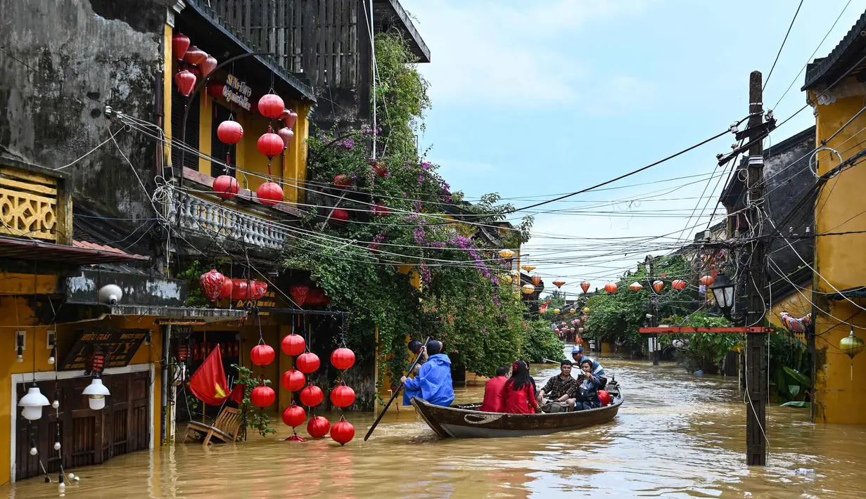 Orang-orang menyusuri jalan yang terendam banjir dengan perahu setelah hujan deras di Hoi An, Vietnam, Kamis 30 Oktober 2025. Sedikitnya sembilan orang tewas dan lima lainnya masih dinyatakan hilang. (NHAC NGUYEN/AFP)