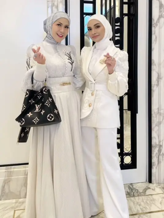 Venna Melinda juga hadir mengenakan atasan lengan panjang berkerah tinggi, serta bordiran bunga, dipadukan rok flowy putih panjang. [@vennamelindareal]