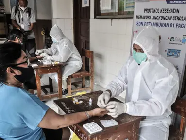 Tim medis dari Polda Metro Jaya saat menggelar rapid test kepada warga di SDN 01 Petamburan, Jakarta, Minggu (22/11/2020). Polda Metro Jaya menggelar rapid test gratis kepada warga Petamburan sebagai langkah mencegah penyebaran Covid-19. (merdeka.com/Iqbal S. Nugroho)