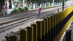 Pejalan kaki menyeberangi perlintasan kereta api di Tanjung Barat, Jakarta, Senin (7/1). Meskipun sering terjadi kecelakaan dan dipasangi pagar, pejalan kaki tetap melompati pagar dari pada menggunakan fasilitas JPO. (Liputan6.com/Immanuel Antonius )
