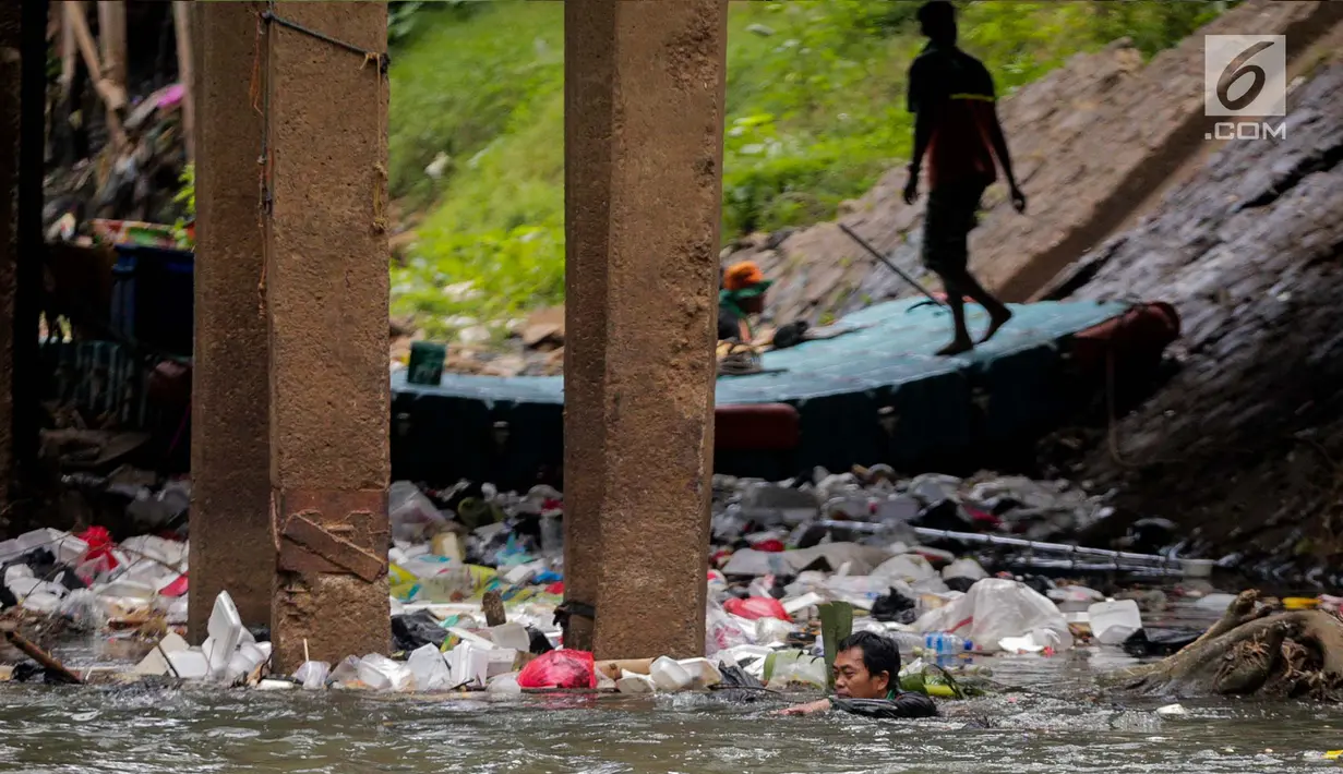 Petugas PPSU berenang untuk membersihkan tumpukan sampah yang tersangkut  di aliran anak kali Ciliwung, Jakarta, Senin (22/7/2019). Pembersihan sungai dari berbagai sampah tersebut dimaksudkan agar tidak ada penumpukan sampah dan sedimentasi saluran di sepanjang sungai. (Liputan6.com/Faizal Fanani)
