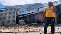Seorang pria berbicara di telepon selulernya di dekat sebuah bangunan yang rusak akibat gempa di Palu, Sulawesi Tengah, Selasa 16 Juni 2026. (AP Photo/Josua Marunduh)