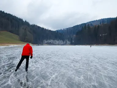 Seorang wisatawan asyik bermain ice skating atau seluncur es di atas sungai Doubs yang membeku di perbatasan Perancis Les Brenets, Swiss, Senin (2/1). Sungai ini menjadi objek wisata es yang diminati warga. (REUTERS/Denis Balibouse)