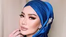 Reza menutup penampilannya dengan hijab lilit biru satin dengan aksesori silver dan makeup yang bold [@rezaartameviaofficial]