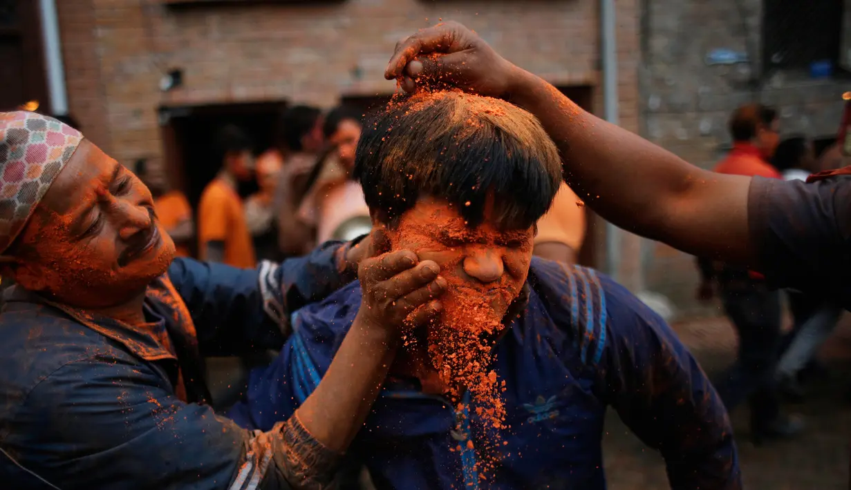 Warga menaburkan bubuk vermillion saat perayaan sindoor Jatra festival di Bhaktapur, Nepal (15/4). Dalam festival tersebut warga Nepal menaburkan serbuk berwarna oranye untuk merayakan 'Sindoor Jatra'. (AP Photo/Niranjan Shrestha)