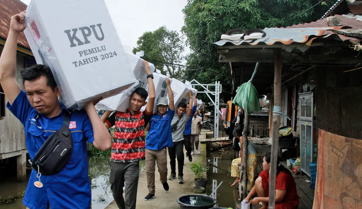 Petugas pemilu membawa kotak suara saat mendistribusikan perlengkapan pemilu ke desa-desa terpencil, di Pemulutan, Sumatra Selatan, Indonesia, Selasa, 13 Februari 2024. (AP Photo/Muhammad Hatta)