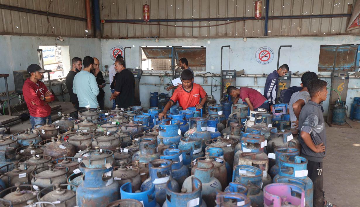 Pekerja Palestina mengisi tabung gas di stasiun pengisian resmi di kamp pengungsi Nuseirat, di bagian tengah Jalur Gaza, pada Senin 10 November 2025. Meski dalam jumlah terbatas, pasokan bahan bakar gas untuk memasak mulai didistribusikan ke warga Gaza. (Eyad Baba/AFP)