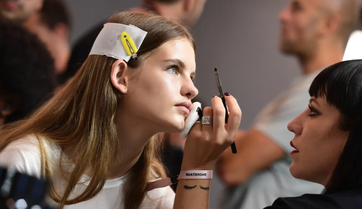 Seorang model saat di rias di belakang panggung sebelum tampil mengenakan busana Women Spring/Summer 2019 karya rumah mode N.21 selama Milan Fashion Week di Italia (19/9). (AFP Photo/Miguel Medina)