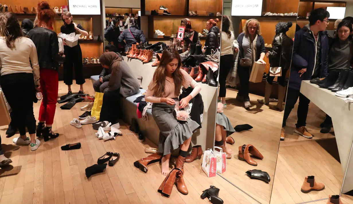 Calon pembeli menjajal sepatu selama Boxing Day di Department stores Selfridges, London, Selasa (26/12). Boxing Day merupakan tradisi hari belanja terbesar tahunan yang dirayakan setiap 26 Desember atau sehari setelah Natal. (Daniel LEAL-OLIVAS/AFP)