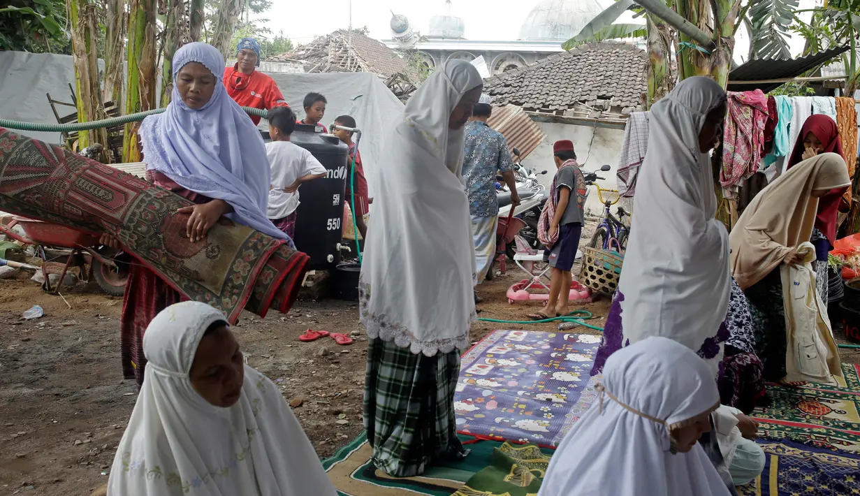 Korban gempa Lombok melaksanakan salat di tempat penampungan sementara di Lombok Barat, Nusa Tenggara Barat (NTB), Sabtu (11/8). Masa tanggap darurat gempa Lombok diperpanjang hingga 25 Agustus 2018. (AP Photo/Firdia Lisnawati)