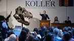 Direktur rumah lelang Koller Cyril Koller (Tengah) memberi isyarat di sebelah tengkorak 'Trinitas' selama penjualan kerangka Tyrannosaurus-Rex (T-Rex) oleh rumah lelang Koller di Zurich, pada 18 April 2023. (Photo by Fabrice COFFRINI / AFP)