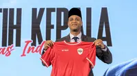 Pelatih kepala baru Timnas Indonesia, Patrick Kluivert berpose dengan memegang jersey dan memakai peci setelah sesi konferensi pers yang berlangsung di Hotel Mulia, Senayan, Jakarta, Minggu (12/01/2025). (Bola.com/Bagaskara Lazuardi)