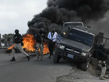 Polisi meninggalkan kendaraan mereka saat demonstrasi yang berubah menjadi kekerasan di Cap-Haitien, Haiti, Kamis (22/7/2021). Demonstrasi menuntut keadilan atas pembunuhan Presiden Haiti Jovenel Moise terus berlanjut dan menimbulkan kerusuhan. (AP Photo/Matias Delacroix)