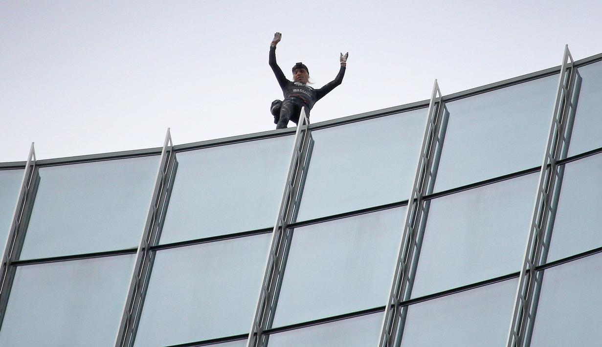 Pendaki kota Prancis, Alain Robert, yang dikenal sebagai "French Spiderman", mengangkat tangannya setelah memanjat gedung Skyper setinggi 153,8 m di Frankfurt am Main, Sabtu (28/9/2019). (AFP Photo/Daniel Roland)