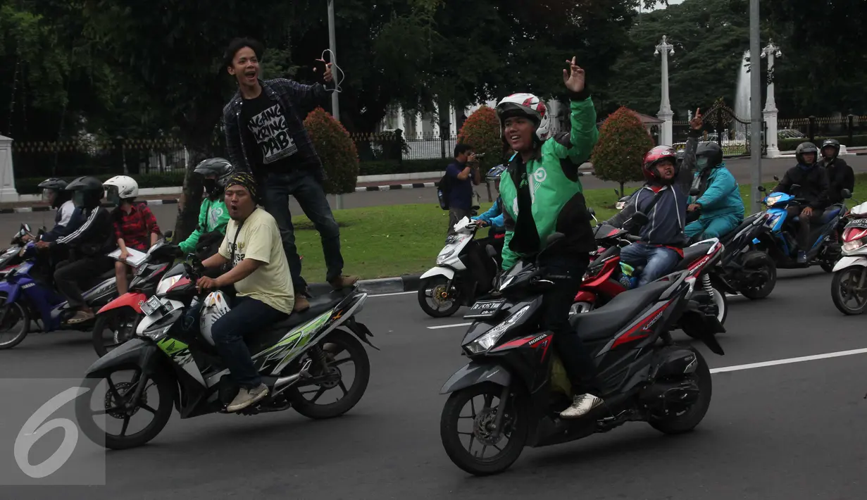 Pengemudi ojek online melintas di depan Istana Negara saat aksi ribuan supir menuntut pembekuan transportasi online, Jakarta, Selasa (22/3). Aksi tersebut berujung ricuh karena terjadi aksi saling lempar batu. (Liputan6.com/Gempur M Surya)