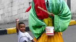 Foto pada 26 April 2019, memeprlihatkan Hassan (4) memegang ember kecil untuk saweran bergabung bersama yang lainnya mengamen ondel-ondel di jalanan Jakarta. Seiring berjalan waktu, ondel-ondel yang dahulu sebagai ikon kesenian Betawi kini mudah ditemui di jalanan ibu kota. (GOH CHAI HIN / AFP)