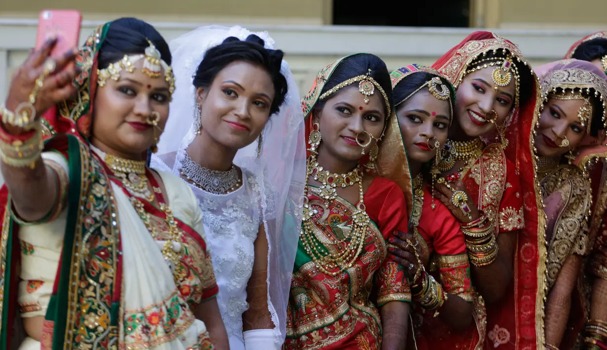 Sejumlah pengantin perempuan foto bersama saat nikah massal di Surat, India, Minggu (23/12). Pernikahan di India adalah urusan mahal. (AP/Ajit Solanki)