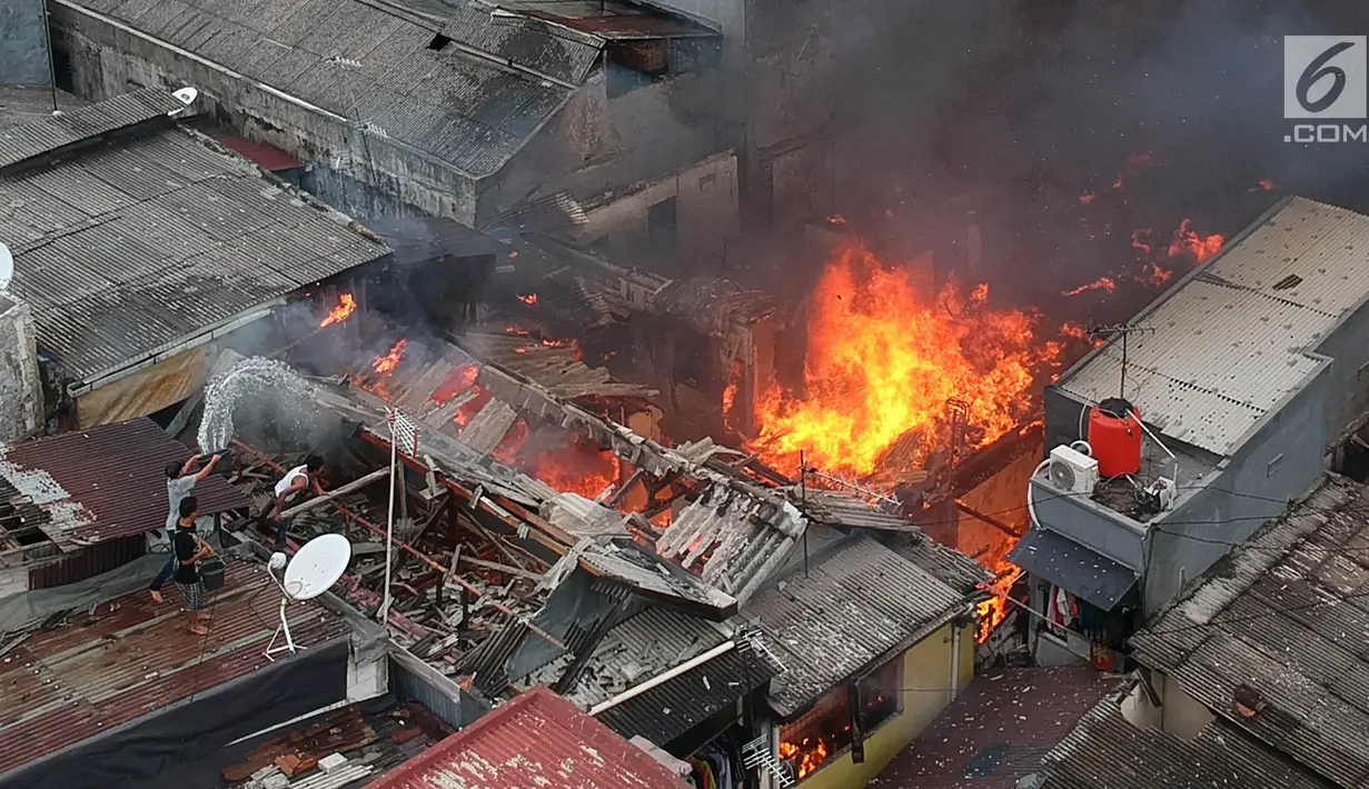Warga berusaha memadamkan api dengan menyiramkan air saat terjadi kebakaran di kawasan Tanah Tinggi, Johar Baru, Jakarta, Selasa (26/6). Sebanyak 18 unit mobil pemadam kebakaran telah diterjunkan ke lokasi. (Liputan6.com/Arya Manggala)