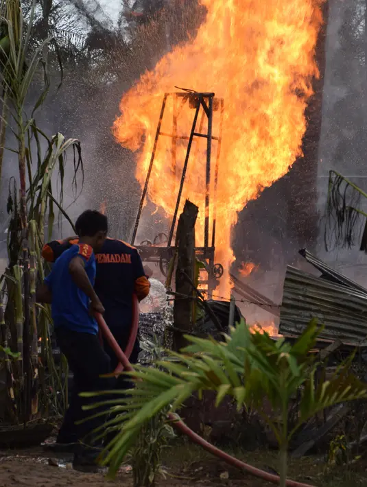 Petugas pemadam kebakaran berada di lokasi kebakaran pengeboran sumur minyak ilegal milik warga di Peureulak, Provinsi Aceh, Rabu (25/4). Hingga sekarang semburan api yang mencapai ketinggian 100 meter itu belum bisa dipadamkan. (ILYAS ISMAIL/AFP)