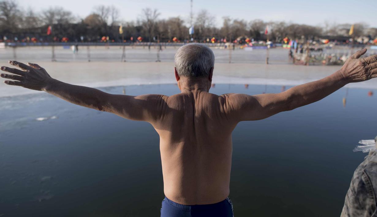 Seorang pria bersiap untuk melompat ke dalam danau Hou Hai yang beku di Beijing, China (24/1). (AFP Photo/Nicolas Asfouri)
