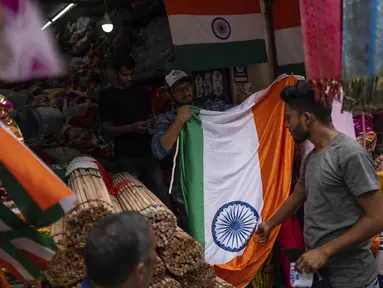 Seorang penjaga toko mengangkat bendera nasional untuk dijual menjelang Hari Kemerdekaan India di Mumbai, India, Selasa, 2 Agustus 2022. Perdana Menteri India Narendra Modi telah mengimbau warga untuk mengibarkan atau memajang bendera nasional di Hari Kemerdekaan pada 15 Agustus. (AP Photo/Rafiq Maqbool)