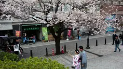 Pengunjung berpose di dekat Bunga Sakura di kawasan Asakusa Tokyo, Kamis (6/4). Memasuki bulan April, bunga Sakura mulai bermekaran dan menggoda mata untuk melihatnya.  (AFP Photo/ Behrouz MEHRI)