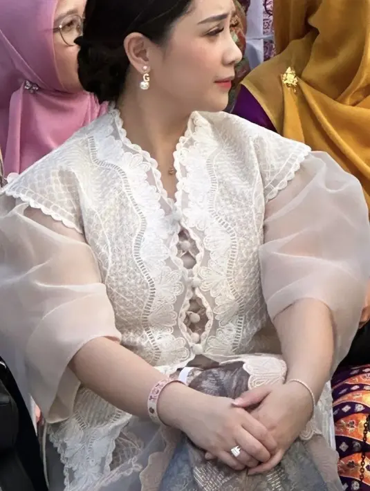 Nagita tampilan dengan makeup natural mengenakan blush on pink, lipstik merah cherry matte, dan bulu mata yang lentik. Dengan gaya rambut sanggul modern. Ia pun tampil dengan anting mutiara yang memiliki detail huruf G, lengkap mengenakan, gelang, cincin, kalung. [Instagram/@loemongga]