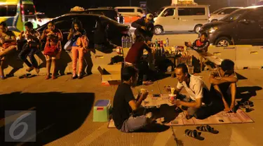 Sejumlah pemudik tengah beristirahat sambil menikmati makanan yang dijajakan pedagang di pinggir Tol Cikopo, Jawa Barat, Jumat (1/7). Kemacetan di sepanjang jalur tersebut dimanfaatkan pedagang untuk berjualan di sekitar lokasi (Liputan6.com/Angga Yuniar)