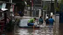 Warga duduk di atas mobil saat banjir merendam jalan dan rumah di RT 003/05, Pejaten, Jakarta, Sabtu ( 20/2/2021). Curah hujan yang tinggi sejak malam hingga dini hari mengakibatkan sejumlah kawasan terendam banjir. (merdeka.com/Imam Buhori)