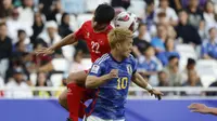 Gelandang Vietnam, Khuat Van Khang dan gelandang Jepang, Ritsu Doan melompat untuk menyundul bola dalam laga Grup D Piala Asia 2023 Qatar di Stadion Al-Thumama, Doha, Qatar, Minggu (14/1/2023). (AFP/Karim Jaafar)
