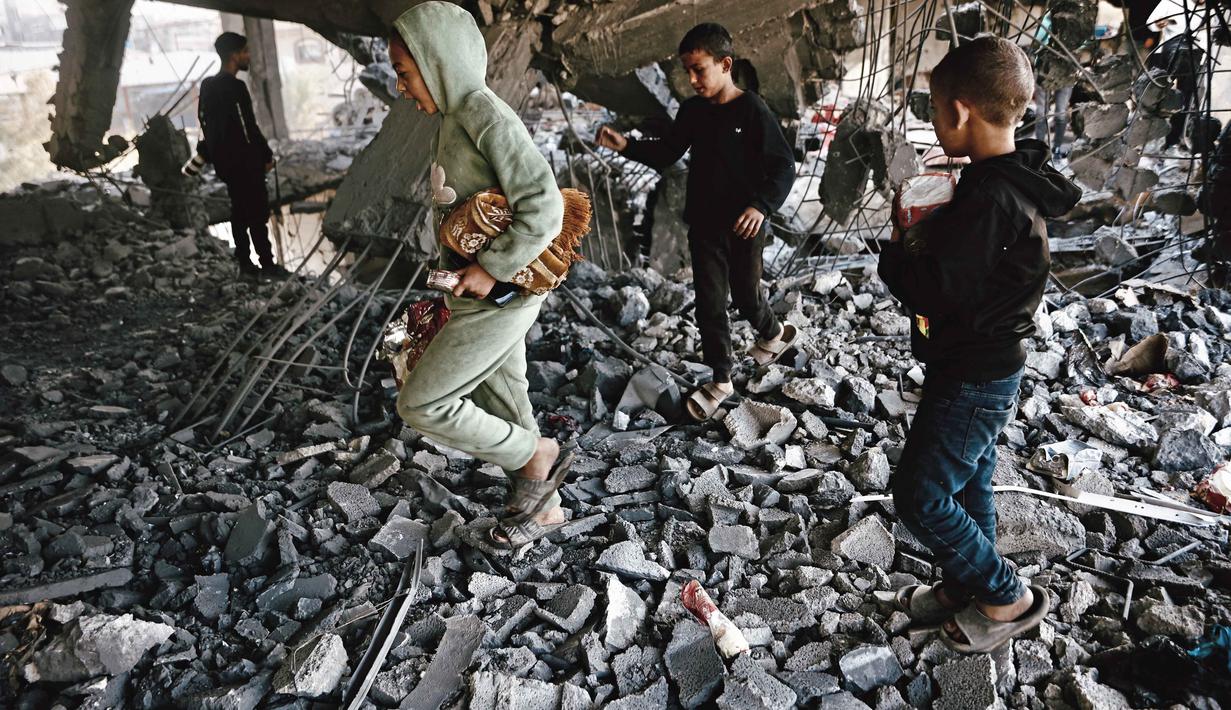 Anak-anak Palestina memeriksa puing-puing bangunan yang rusak milik Kementerian Wakaf Agama, yang digunakan sebagai tempat penampungan bagi pengungsi di kawasan Zeitoun, Kota Gaza, pada Kamis 20 November 2025, sehari setelah bangunan tersebut menjadi sasaran serangan militer Israel. Militer Israel kembali melancarkan rangkaian serangan ke sejumlah wilayah Gaza pada Rabu (19/11/2025). (Omar AL-QATTAA/AFP)