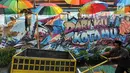 Warga melintasi gambar mural/grafiti di Kampung Bekelir, Jalan Perintis Kemerdekaan, Kota Tangerang, Banten, Selasa (17/4). Kampung Bekelir pada 10 tahun lalu merupakan kawasan yang kumuh. (Merdeka.com/Arie Basuki)