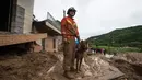 Anggota tim penyelamat dan seekor anjing pelacak tengah bertugas di Yuanshan, sebuah desa di Kota Dahe, Provinsi Hubei, China (8/7/2020). Seorang wanita lansia berhasil diselamatkan beberapa jam setelah dirinya dan delapan orang lainnya terkubur akibat longsor yang dipicu hujan. (Xinhua/Xiao Yijiu)