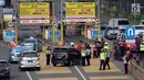 Petugas mengarahkan kendaraan berplat genap berputar balik di Gerbang Tol Bekasi Barat 1, Bekasi, Jawa Barat, Selasa (13/3). Hari kedua penerapan ganjil genap, masih banyak kendaraan berputar balik di gerbang tol tersebut. (Liputan6.com/Arya Manggala)