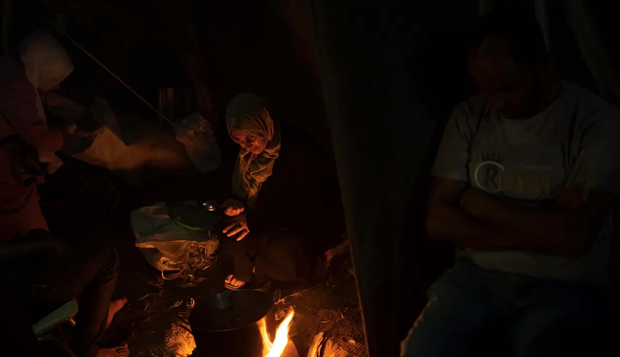 Warga Palestina memasak makanan dengan peralatan seadanya. (AP Photo/Fatima Shbair)