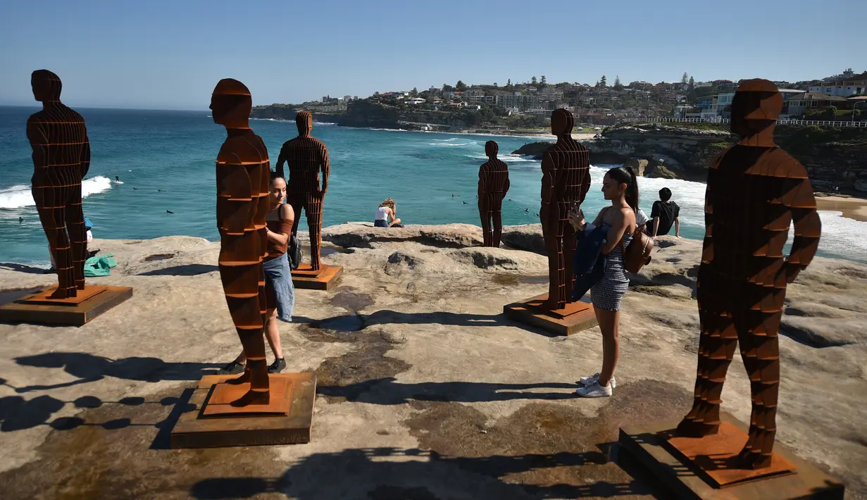 Pengunjung berpose dengan patung berjduul Shifting Horizons karya April Pine saat pameran Sculpture by the Sea di Sydney, Australia, Jumat (19/10). Pameran patung unik ini dibuka secara umum, tanpa memungut biaya sepeser pun. (PETER PARKS/AFP)