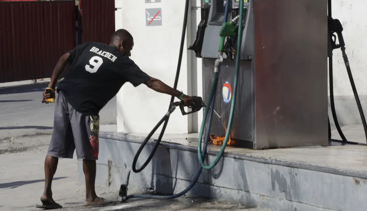 Seorang warga mencoba membakar pom bensin saat demo pemilu di Port-au-Prince, Haiti (18/1). Warga menuduh pemilu presiden Haiti berjalan curang yang menyebabkan kemarahan warga hingga membakar fasilitas umum. (REUTERS/Andres Martinez Casares)