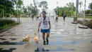 Wisatawan membawa dua ekor anjing saat mengunjungi Senayan Park, Jakarta, Rabu (9/12/2020). Libur Nasional Pilkada Serentak 2020 dimanfaatkan sebagian warga Jakarta dan sekitarnya untuk mengunjungi tempat rekreasi bersama keluarga. (Liputan6.com/Faizal Fanani)