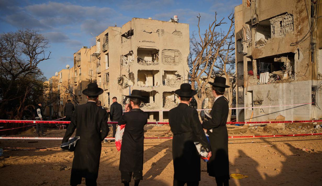Langkah ini diambil setelah evaluasi situasi pascaserangan yang menghantam sejumlah titik, termasuk Arad dan Dimona. Tampak dalam foto, warga melihat bangunan tempat tinggal yang rusak parah akibat serangan rudal Iran di Arad, Israel Selatan, Minggu, 22 Maret 2026. (AP Photo/Ohad Zwigenberg)