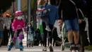 Keluarga dengan anak-anak mereka berjalan di sepanjang bulevar di Barcelona, Spanyol (26/4/2020). Dengan mulai lambatnya kenaikan angka kasus terjangkit membuat warga Spanyol optimis untuk bangkit kembali. (AP Photo/Emilio Morenatti)