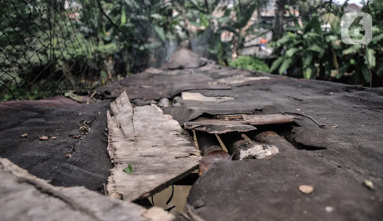 Kondisi jembatan gantung yang sudah tidak layak di kawasan Srengseng Sawah, Jakarta, Sabtu (12/6/2021). Jembatan gantung di atas Sungai Ciliwung tersebut saat ini dalam kondisi tidak layak dan dapat membahayakan keselamatan warga yang melintas. (merdeka.com/Iqbal S. Nugroho)