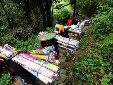 Masyarakat suku Baduy Luar berjalan kaki membawa bantuan berupa karpet untuk didistribusikan kepada korban kebakaran Kampung Cisaban II, Desa Kanekes, Banten, Kamis (01/6). Bantuan didistribusikan untuk 83 rumah. (Liputan6.com/Fery Pradolo)