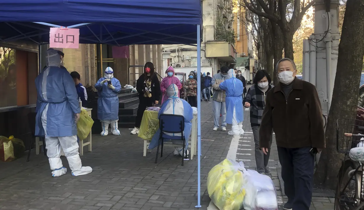 Petugas medis melakukan tes massal untuk warga di area lockdown di distrik Jingan, Shanghai barat (4/4/2022). China telah mengirim lebih dari 10.000 petugas kesehatan dari seluruh negeri ke Shanghai, termasuk 2.000 staf medis militer. (AP Photo/Chen Si)