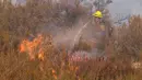 Seorang petugas pemadam kebakaran menyemprotkan air ke titik api saat terjadi kebakaran, Selasa (6/9/2022), dekat Hemet, California. Sekitar 5.000 rumah berada di bawah perintah evakuasi Senin malam ketika api memangkas jalur kehancuran melalui pedesaan yang terbakar. (AP Photo/Ringo H.W. Chiu)