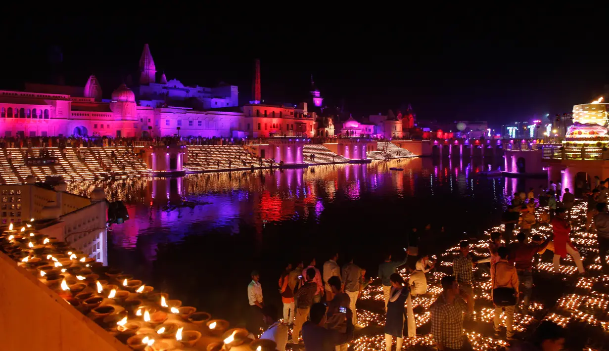 Orang-orang India menyalakan lampu dari tanah liat pada festival Diwali di tepi Sungai Sarayu, Ayodhya, Selasa (6/11). Kota di utara India itu memecahkan rekor dunia Guinness setelah menyalakan 300.150 lampu selama 45 menit. (AP/Rajesh Kumar Singh)